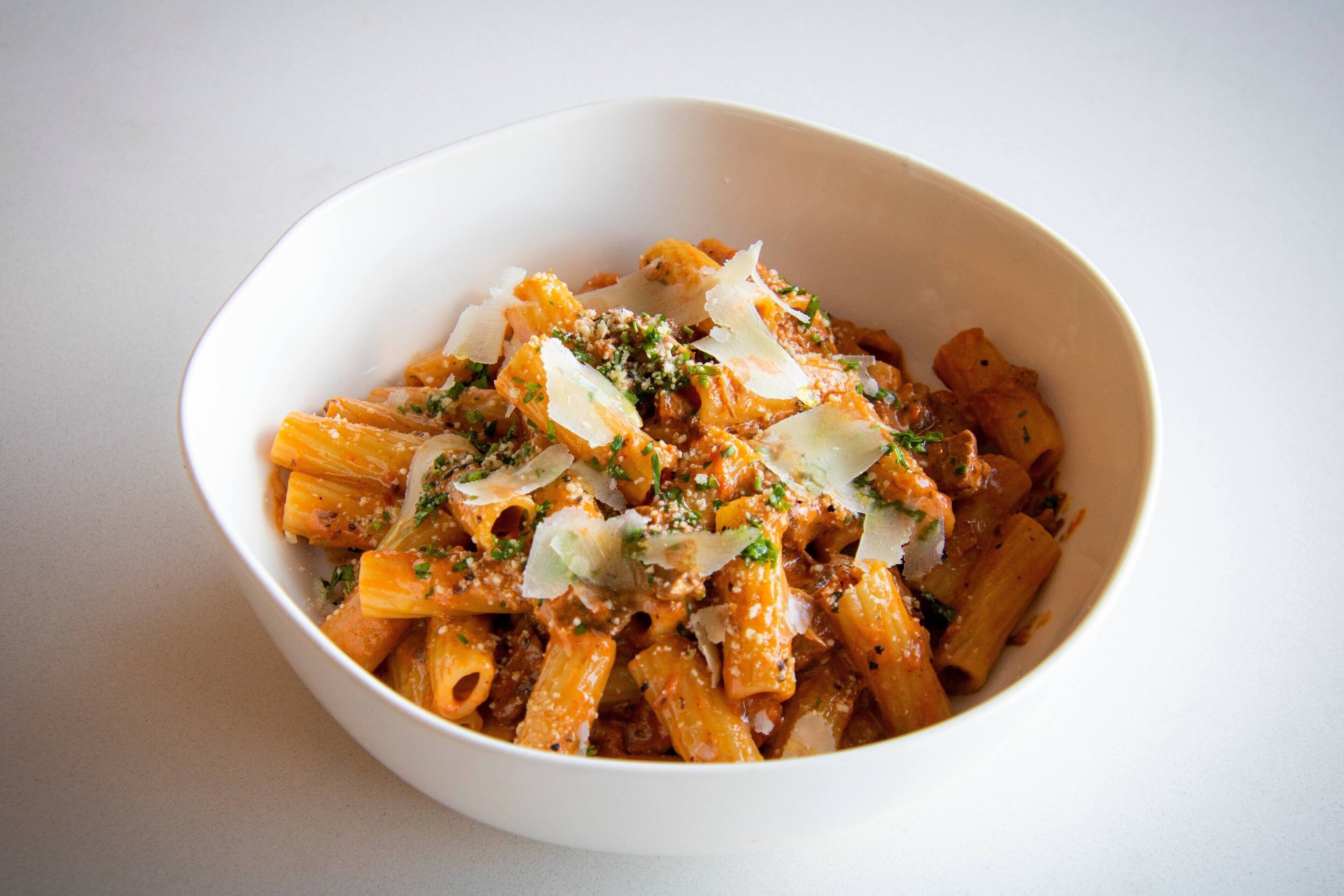 A bowl of pasta with cheese and herbs.