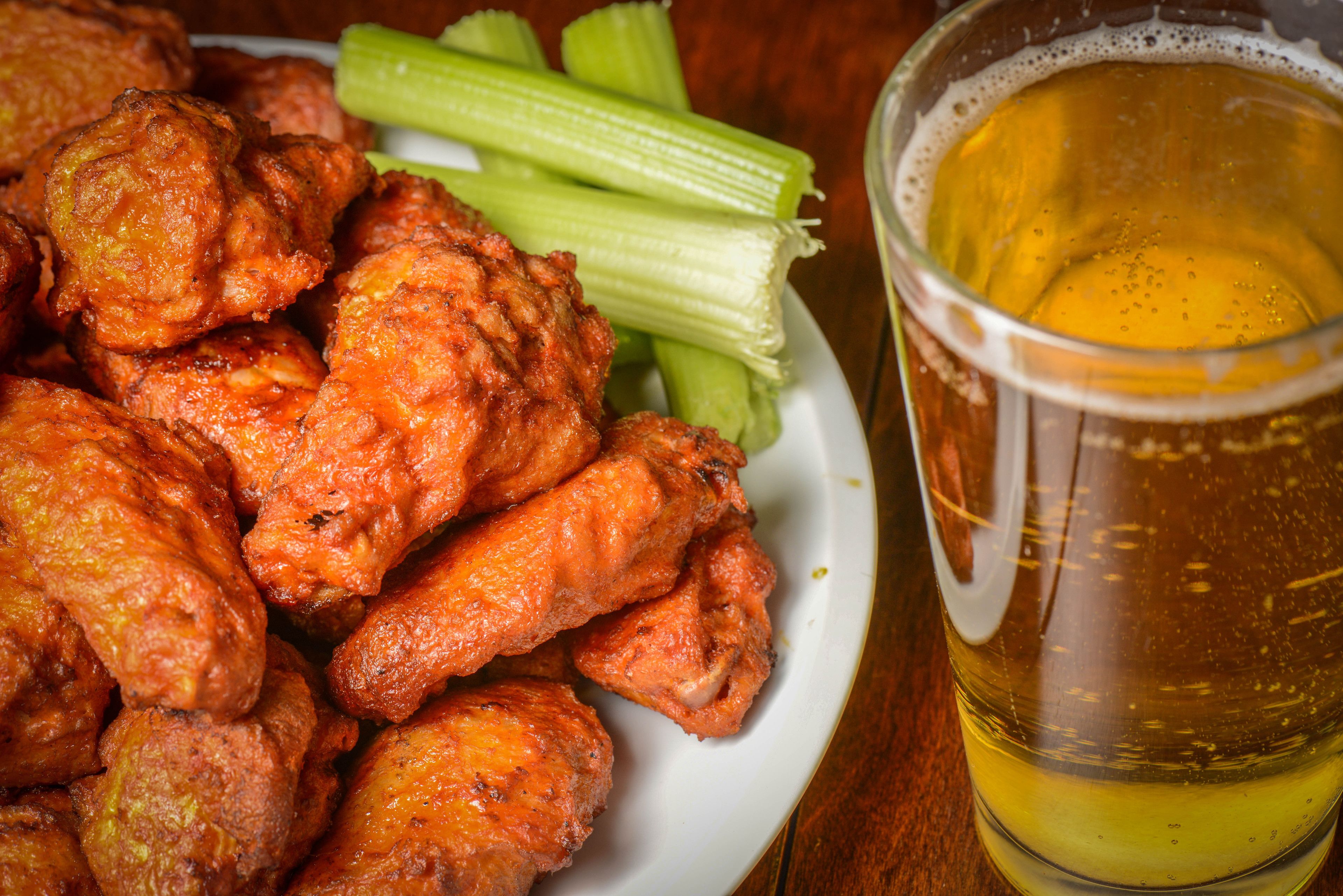 Une assiette d'ailes de poulet, des bâtonnets de céleri et un verre de bière.