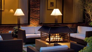 An outdoor seating area with wicker furniture, a fire feature, and lamps. - Providence Marriott Downtown (Providence)