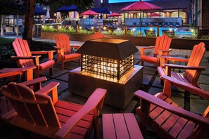 Un área de patio con sillas Adirondack y una chimenea central.