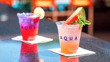 Two drinks on a table with the brand name 'AQUA' visible on the glasses.