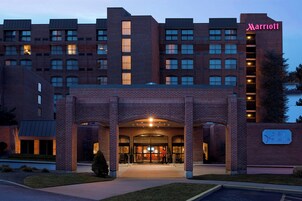 A Marriott hotel entrance with a brick facade, multiple windows, and a well-lit entrance area.