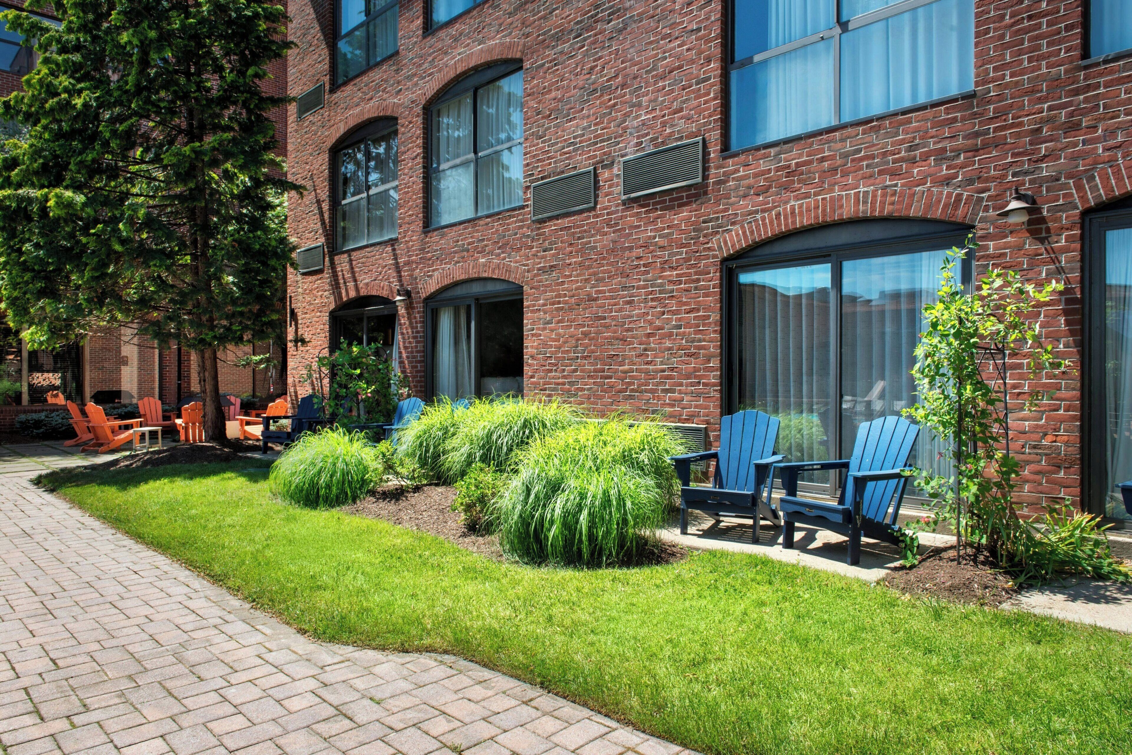 A brick building with large windows, outdoor seating, and a well-maintained lawn.