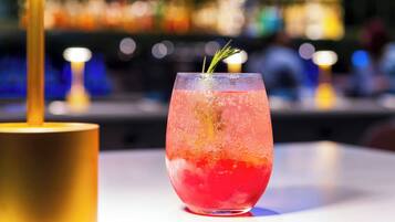Ein Cocktailglas mit Rosmarinzweig auf einer Bar.
