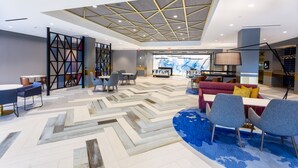 A modern lobby with a geometric patterned floor, contemporary furniture, and a ceiling with recessed lighting and a geometric design. - Providence Marriott Downtown (Providence)