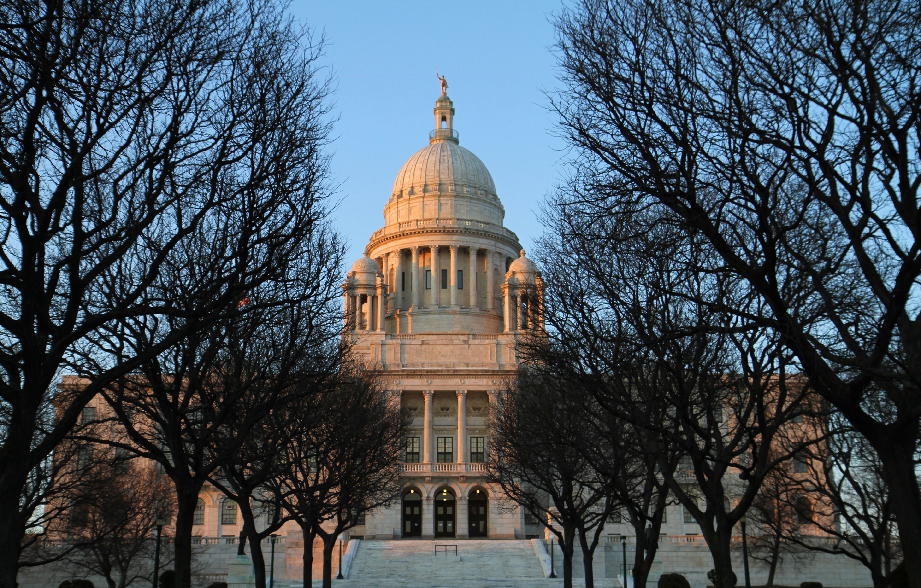 A large, historic building with a prominent dome and columns, surrounded by leafless trees.