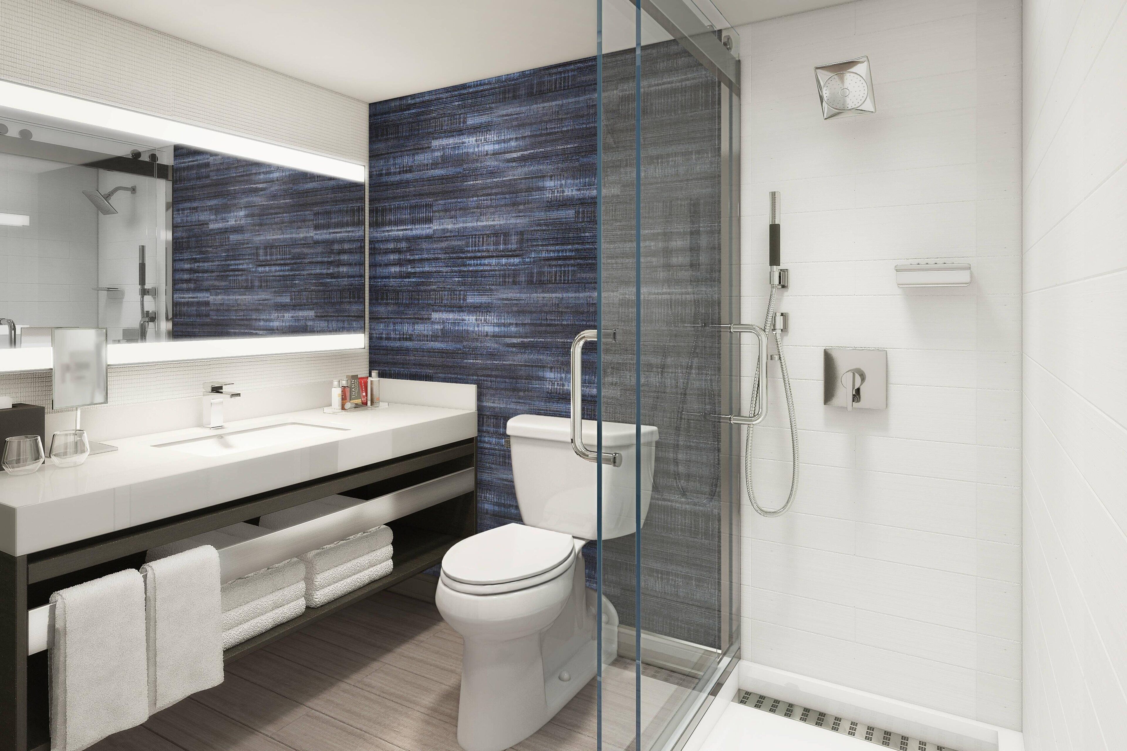 A modern bathroom with a glass shower enclosure, a white sink, and a toilet.