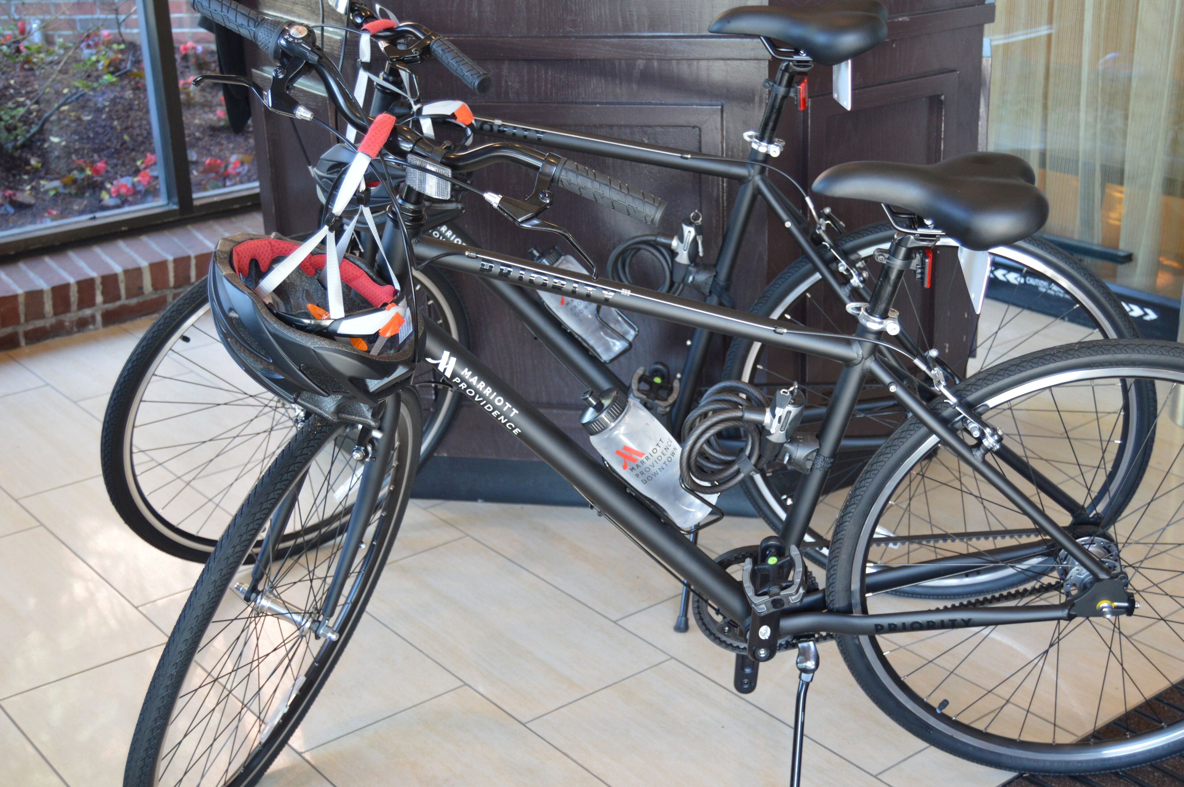 Ein Fahrrad mit schwarzem Rahmen und roten und weißen Akzenten, abgestellt in einem Innenraum mit Blick durch ein Fenster.