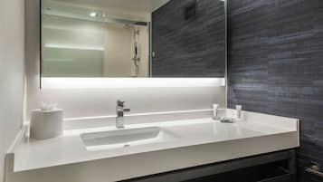 A modern bathroom with a white sink, a large mirror, and a dark textured wall.
