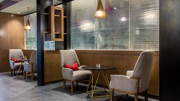 A modern lounge area with three chairs, a small table, and pendant lighting.