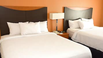 Une chambre d’hôtel avec deux lits, une table de chevet avec une lampe et un téléphone.