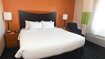 A hotel room with a large bed, two bedside tables, a chair, and a window with curtains.