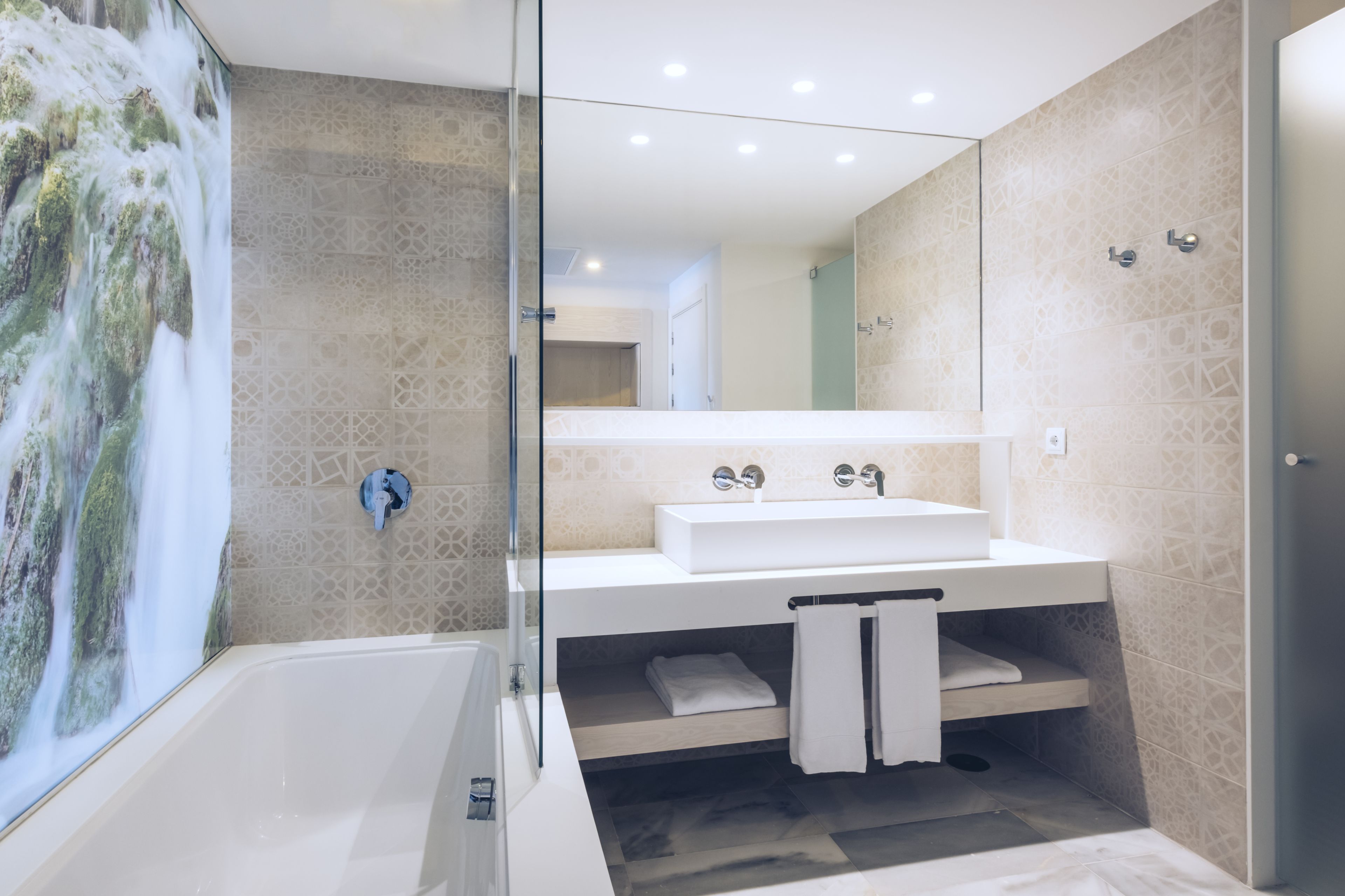 A modern bathroom with a large bathtub, a glass-enclosed shower, and a vanity with a mirror.
