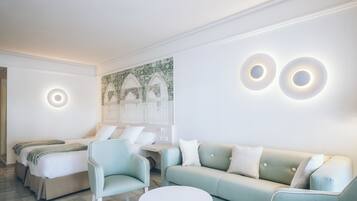 A modern hotel room with a bed, a light green sofa, a round white table, and two wall-mounted circular light fixtures.