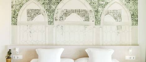 A bedroom with a bed, two bedside tables, and a wall with a decorative tile pattern.