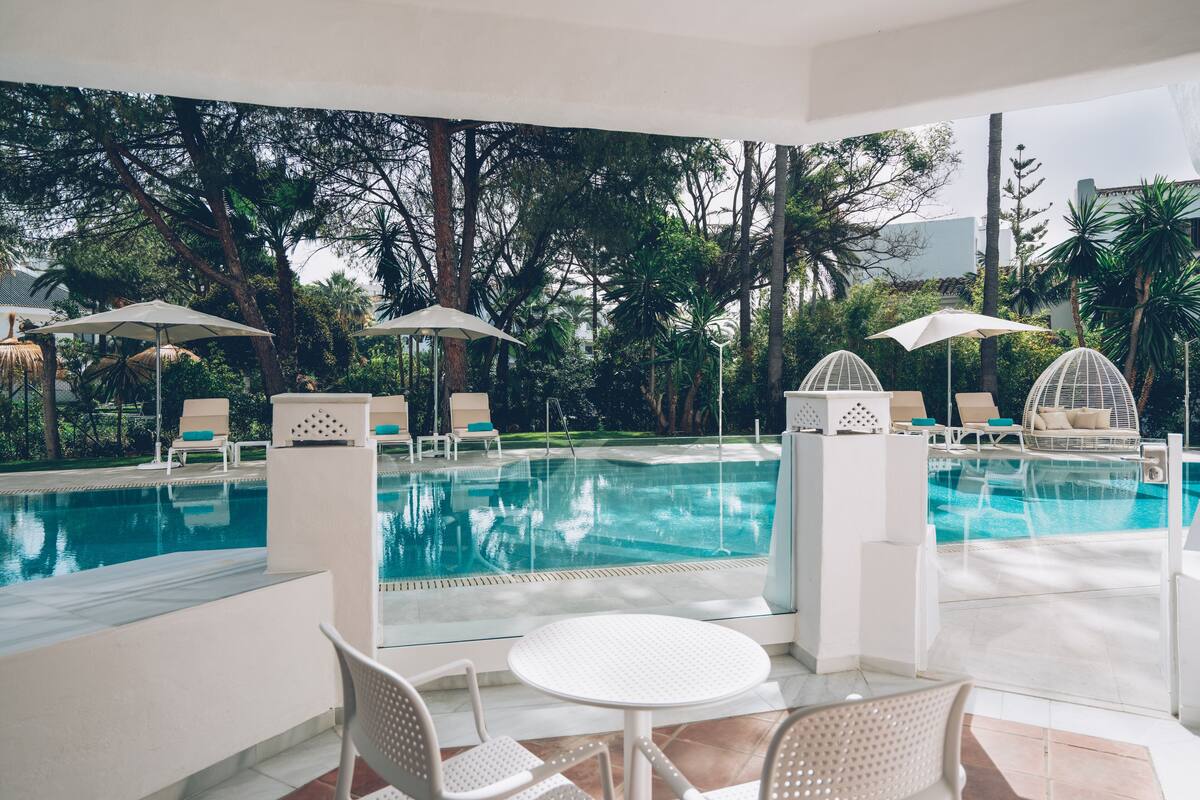 Un espace aménagé au bord de la piscine, offrant une vue dégagée sur celle-ci, et agrémenté de chaises longues et de parasols.