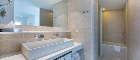 A modern bathroom with a large sink, a mirror, and a shower area.
