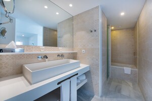 Un baño moderno con un lavamanos grande, un espejo y una zona de ducha.