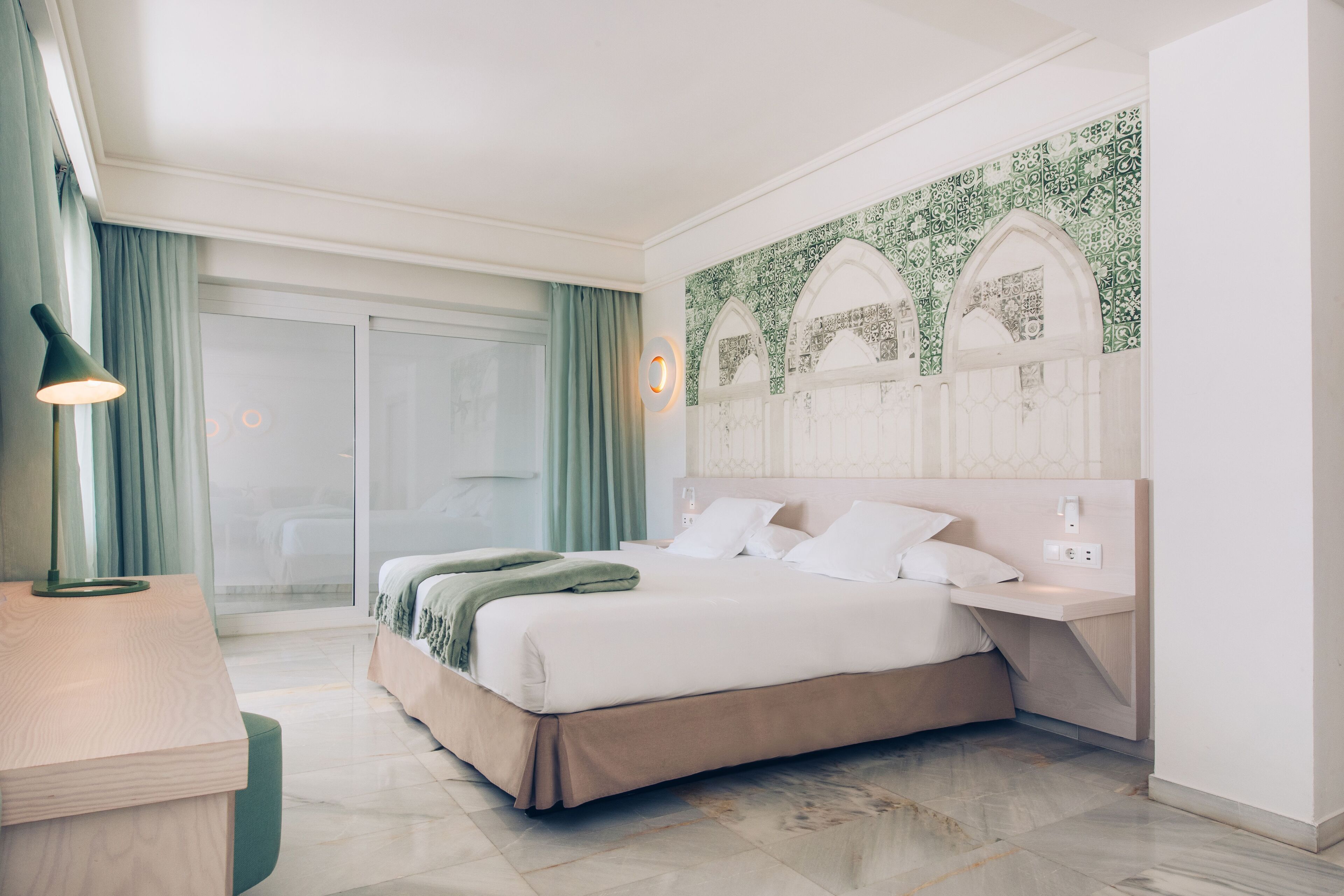 Een moderne hotelkamer met een groot bed, een bureau en uitzicht op de omgeving.