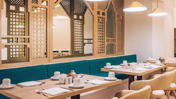 Un restaurante con mesas de madera, bancos acolchados color turquesa e iluminación colgante.