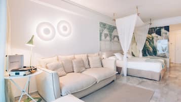 Un dormitorio moderno con una cama grande, un sofá, una mesita con una lámpara y una obra de arte colgada en la pared.