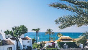 A coastal view with white buildings, palm trees, and a clear blue sky. - Iberostar Selection Marbella Coral Beach (Marbella)