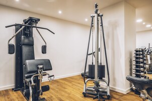 Een fitnessruimte met trainingsapparatuur, waaronder een squatraam, een bankdrukpers en een kabelmachine.