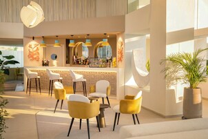 Un área de bar moderna con asientos, una barra con botellas y detalles decorativos en la pared.
