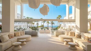 A modern hotel lobby with a large seating area, large windows, and a view of the beach. - Iberostar Selection Marbella Coral Beach (Marbella)