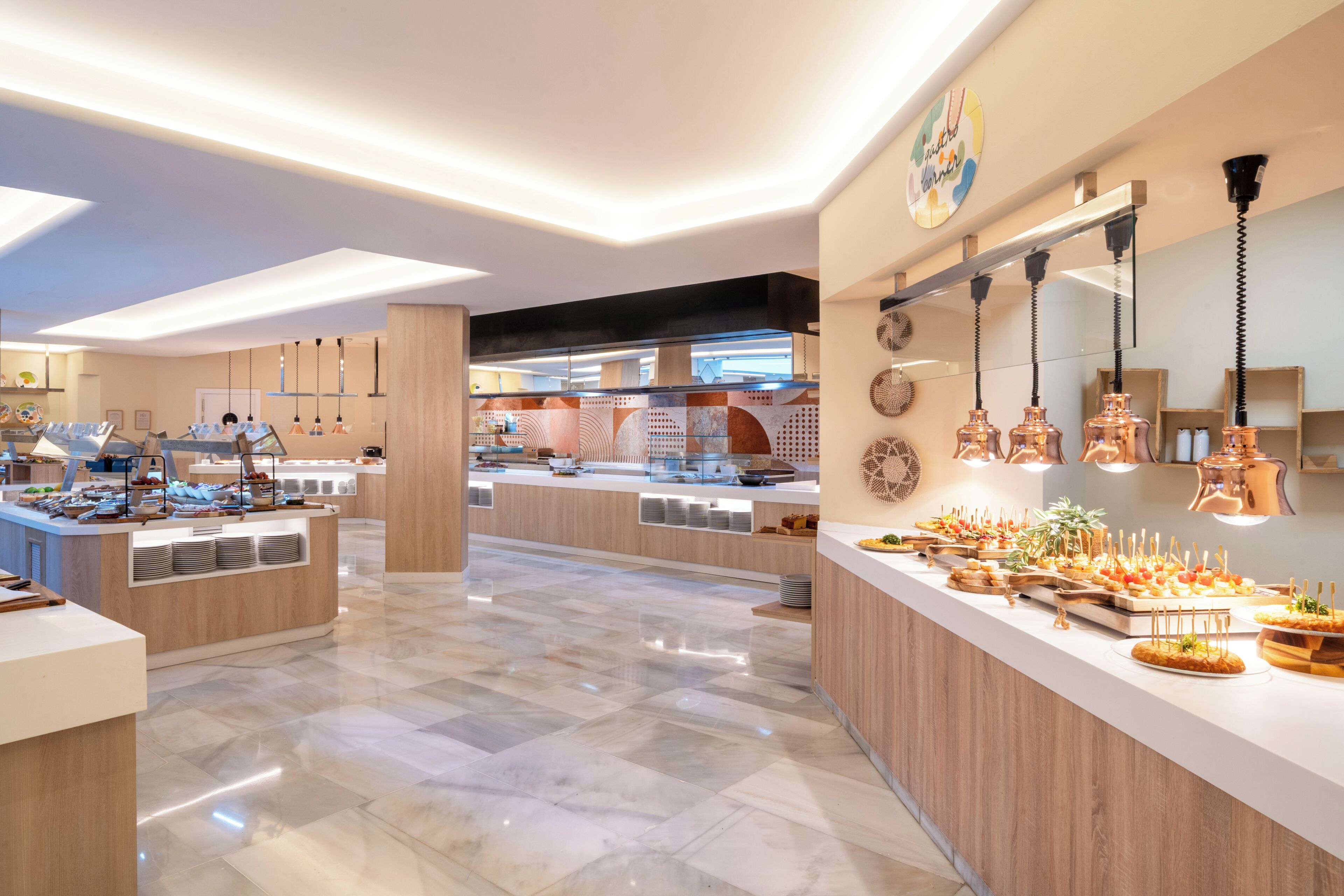 Eine moderne Hotellobby mit einer zentralen Rezeption, einem Frühstücksbuffet mit verschiedenen Speisen und einem sauberen, polierten Boden.