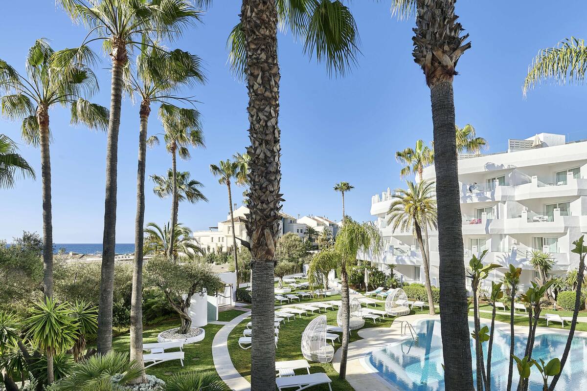 Un complexe hôtelier doté de palmiers, d’une piscine et offrant une vue sur la mer.