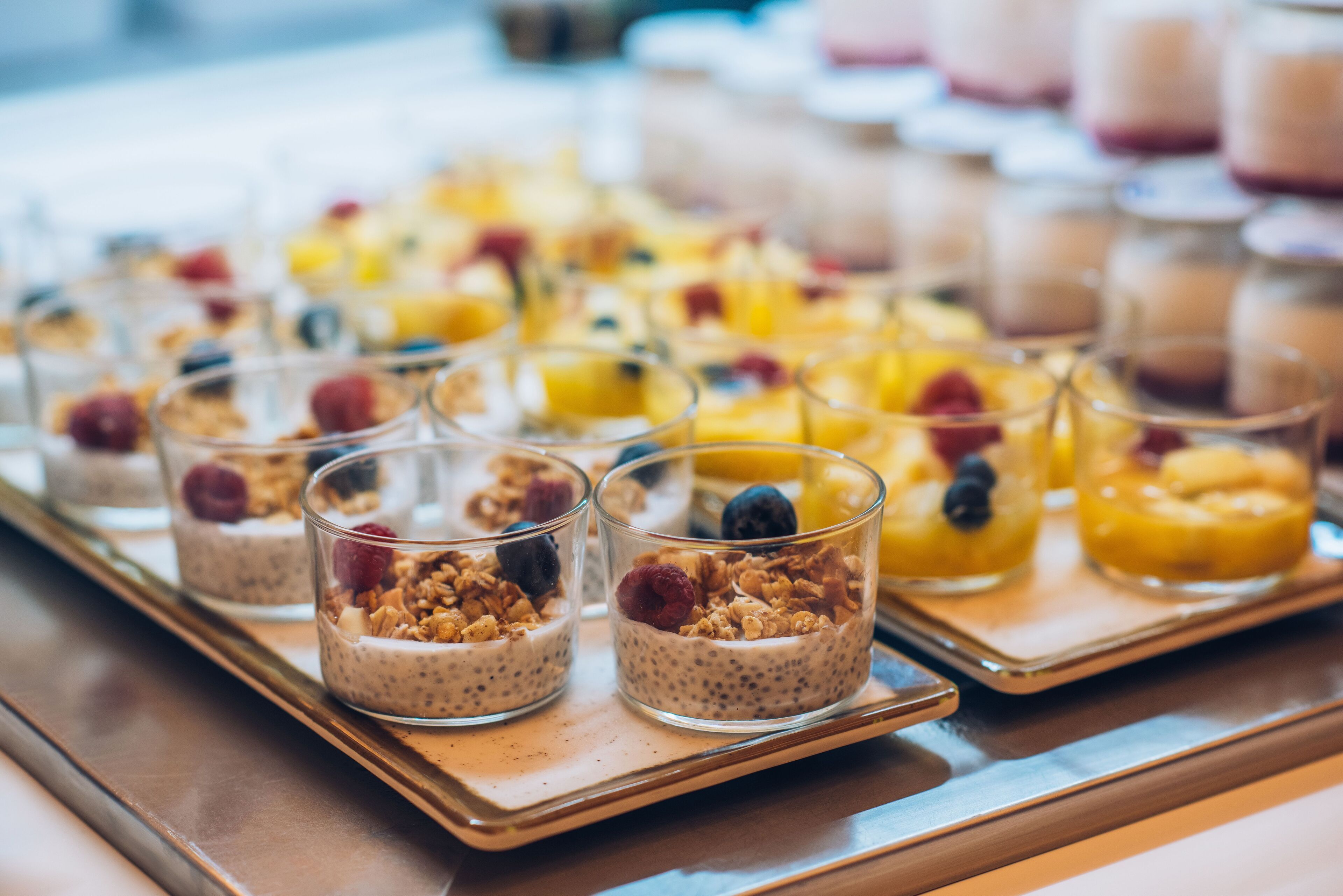 Ein Tablett mit Parfaits, verschiedenen Früchten und Granola.