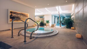 A modern indoor pool area with a glass wall, a painting of a sunset, and a view of a lounge area. - Iberostar Selection Marbella Coral Beach (Marbella)