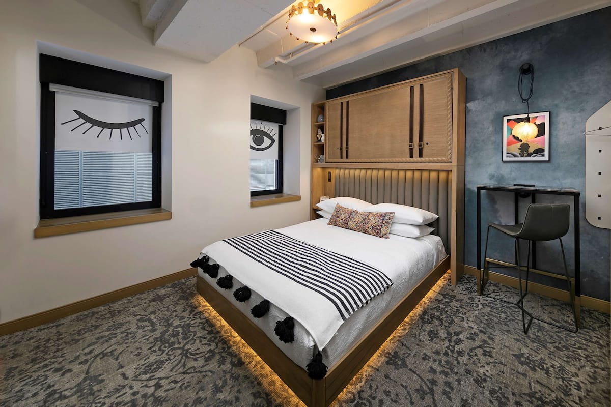 A bedroom with a bed, a desk, and a chair.