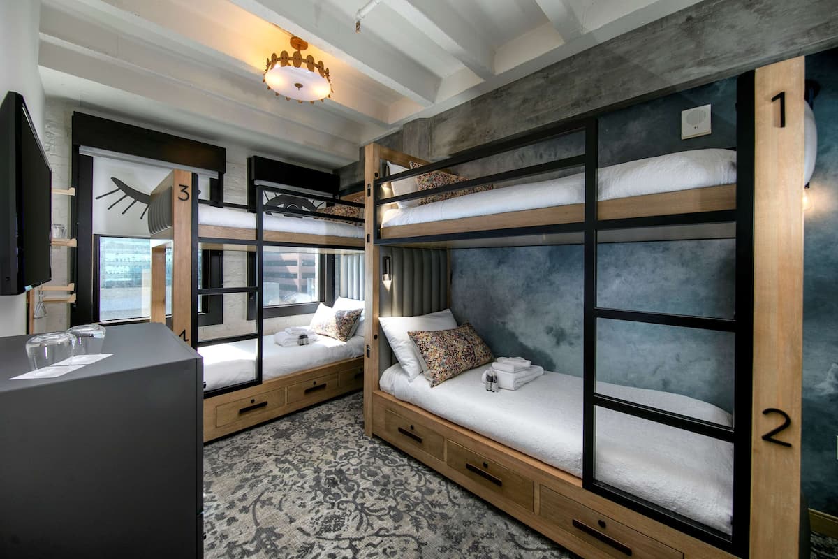 A bunk bed room with a desk, drawers, and a patterned rug.