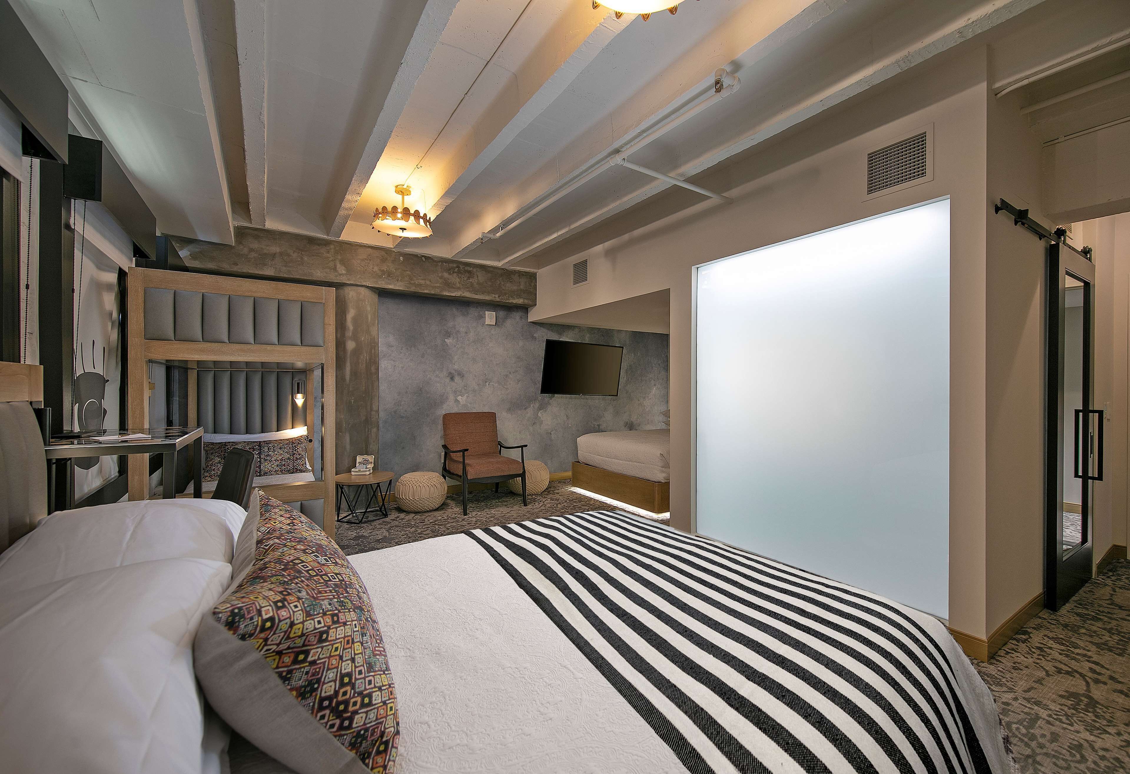 Une chambre d’hôtel moderne équipée d’un grand lit, d’un bureau, d’une chaise, d’un canapé et d’une télévision.