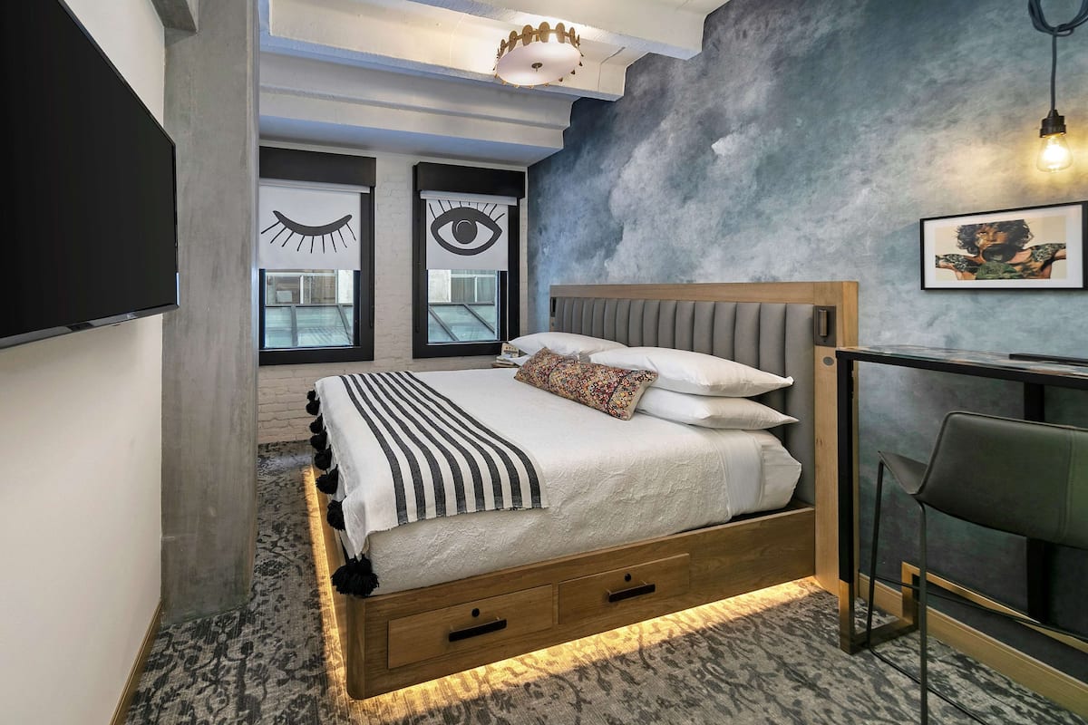 A modern bedroom with a bed, bedside table, and a desk with a chair.