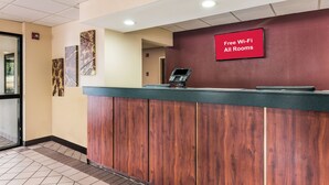 A reception desk with a 'Free Wi-Fi All Rooms' sign, a digital screen, and framed artwork on the wall. - Red Roof Inn Texarkana (Texarkana)