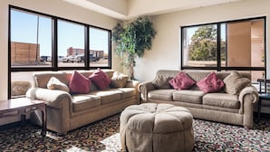 A living room with two sofas, a coffee table, and a large window with a view of a parking lot. - Red Roof Inn Texarkana (Texarkana)