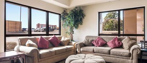 A living room with two sofas, a coffee table, and a large window with a view of a parking lot.