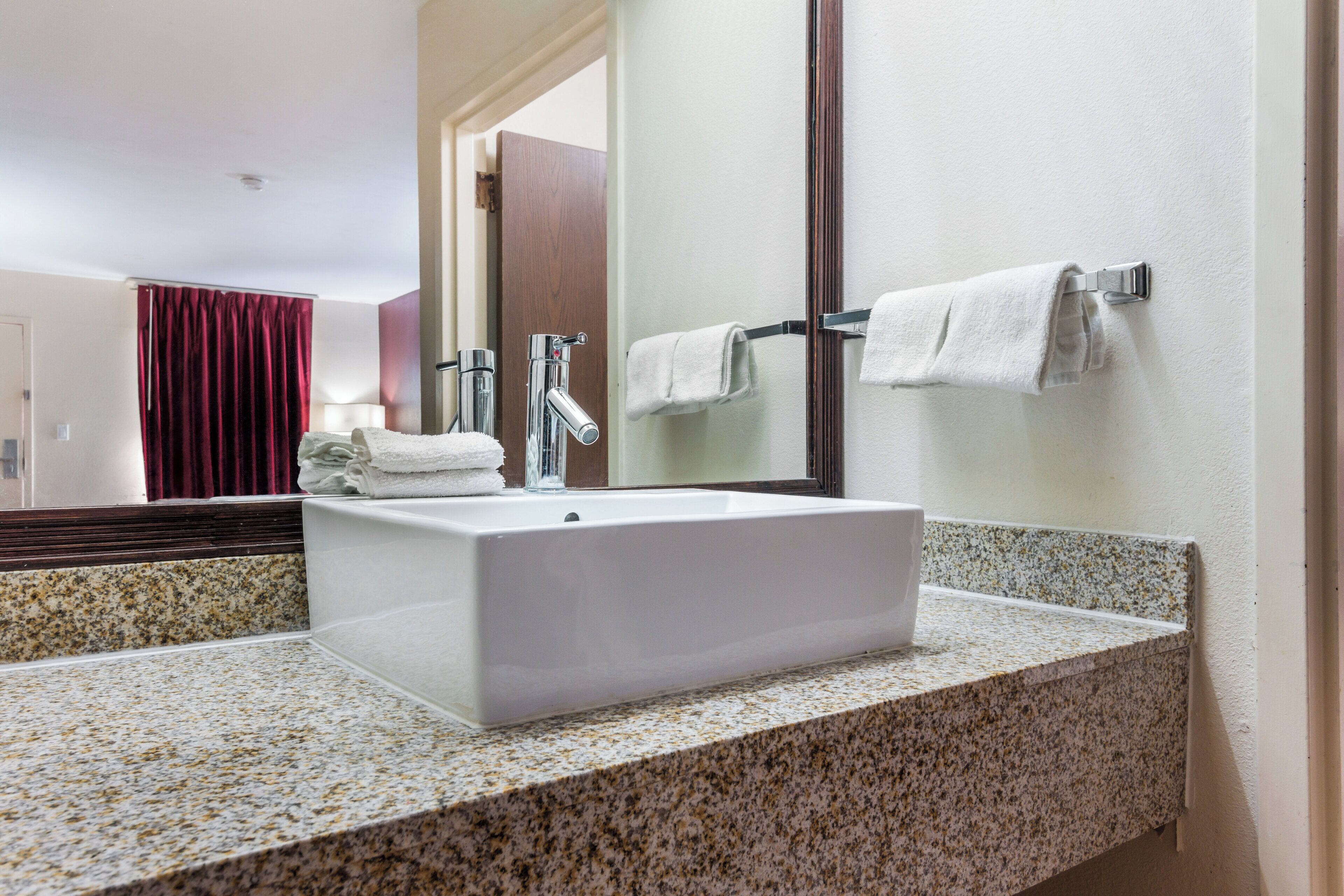 A bathroom with a white sink, a mirror, and a towel rack.