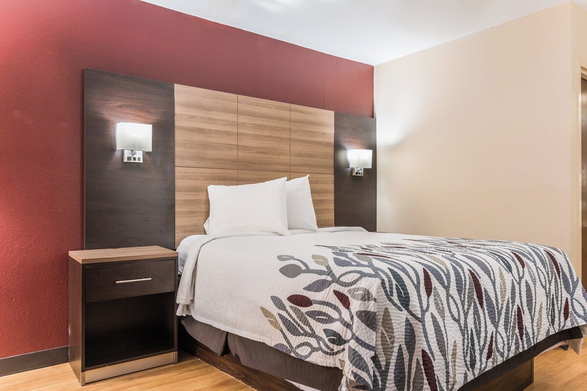 A hotel room with a bed, bedside tables, and wall-mounted lights.