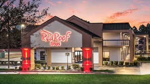 A Red Roof Inn with a modern design, featuring a prominent neon sign, a fire lane, and a well-maintained lawn. - Red Roof Inn Texarkana (Texarkana)