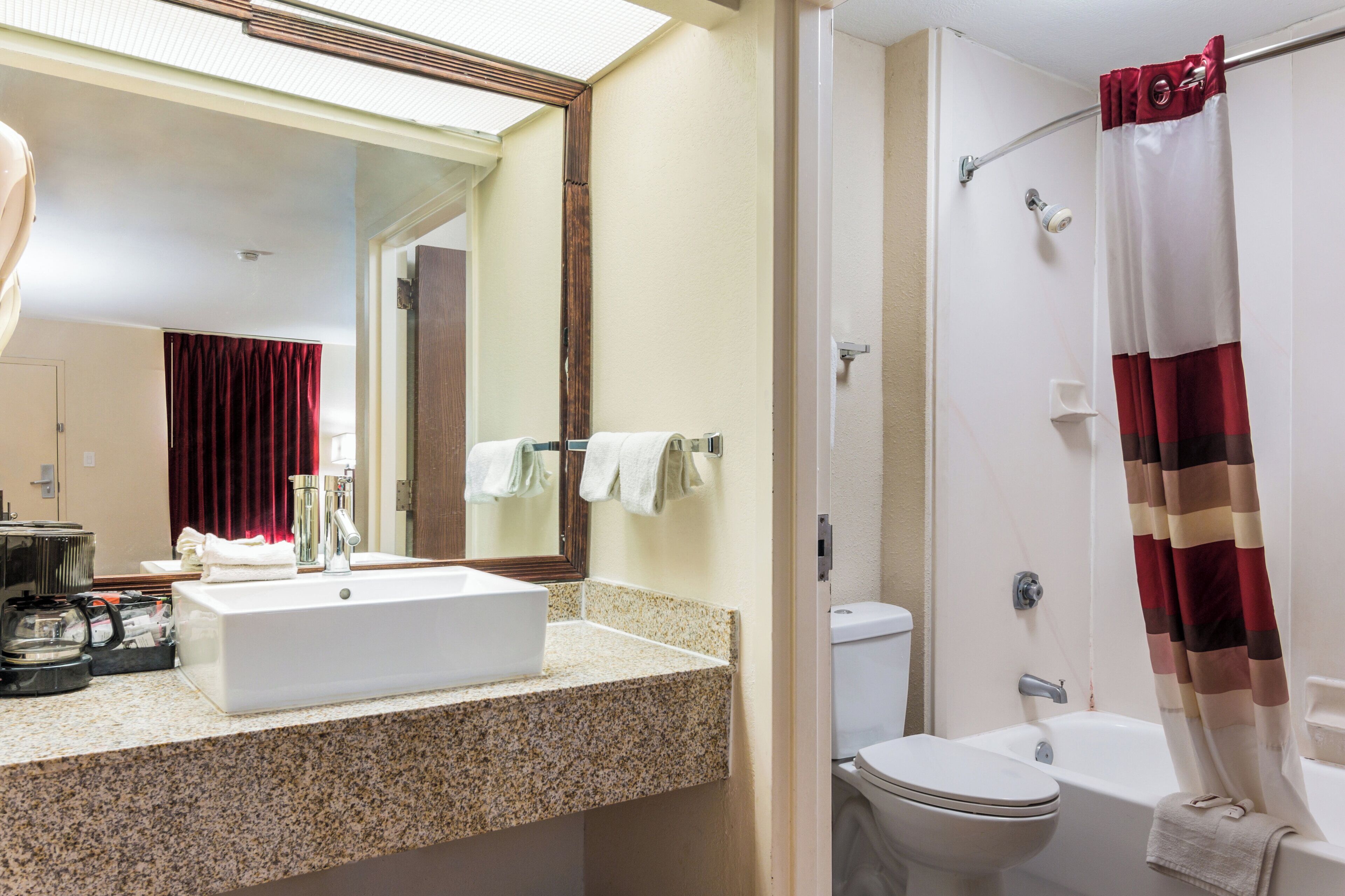 Un baño con lavamanos, espejo, inodoro y ducha.