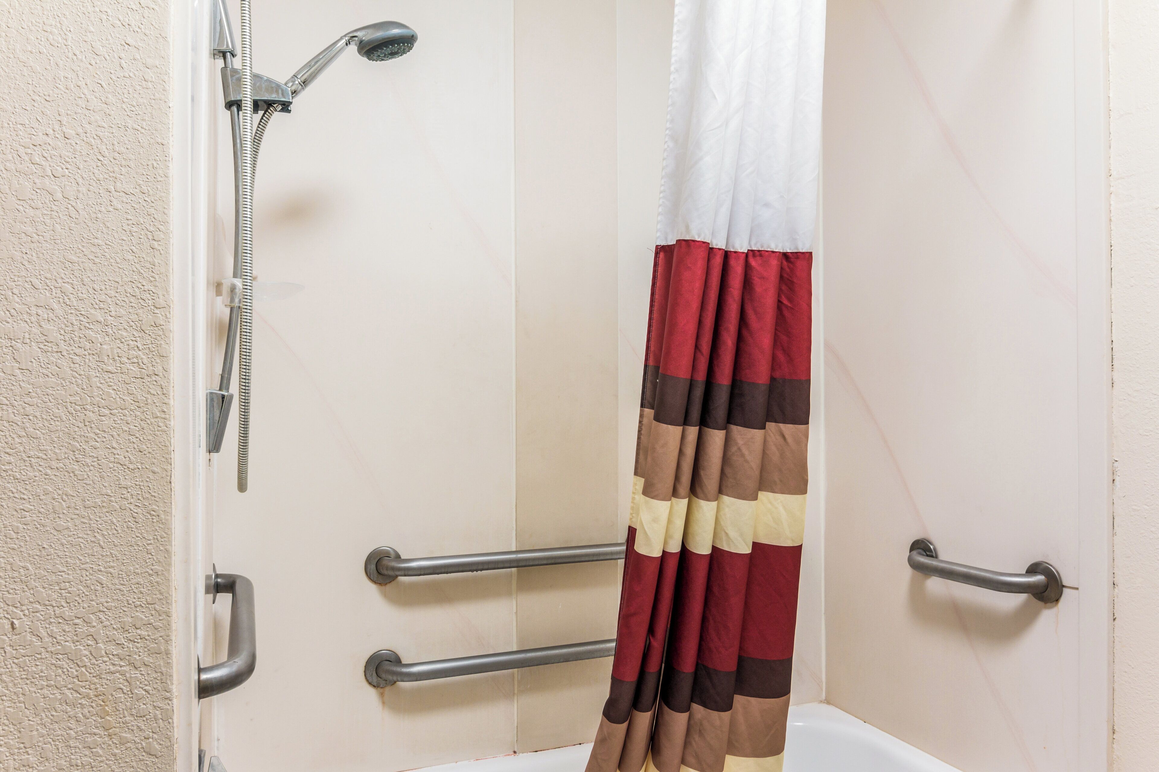 Une salle de bain équipée d’une douche, de barres d’appui et d’un porte-serviettes.
