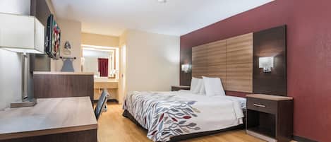 Hotellihuone, jossa on sänky, yöpöytä, lamppu ja näkymä kylpyhuoneeseen.