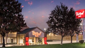 A Red Roof Inn with a prominent neon sign, a parking lot, and a grassy area in front. - Red Roof Inn Texarkana (Texarkana)
