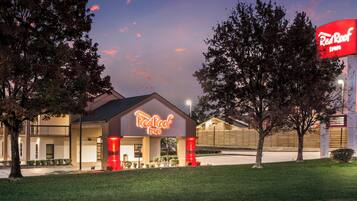 A Red Roof Inn with a prominent neon sign, a parking lot, and a grassy area in front.