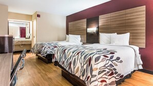 A hotel room with two beds, a wooden headboard, a mirror, and a small desk with a chair. - Red Roof Inn Texarkana (Texarkana)