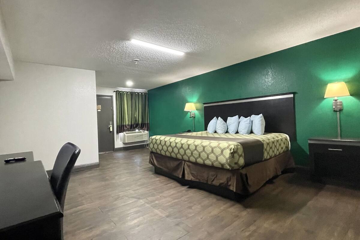 Ein Hotelzimmer mit Bett, Nachttischlampen, einem Schreibtisch und einem Fernseher.